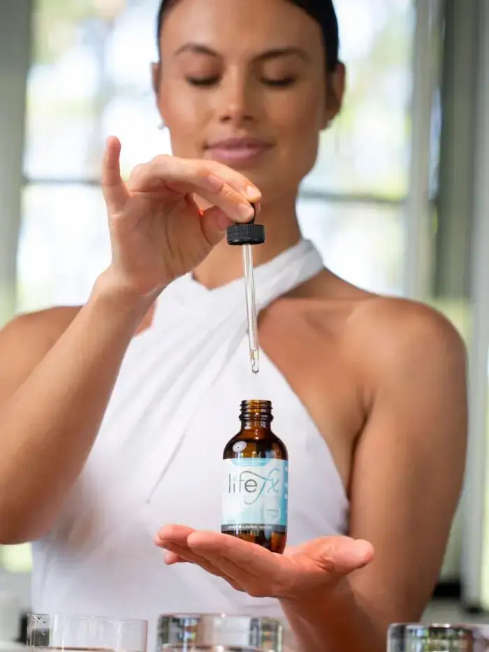 Beautiful woman holding a bottle of LifeFX LIving Water Droplets filled with ionic, crystalline minerals for advanced water purfication and enhancement.