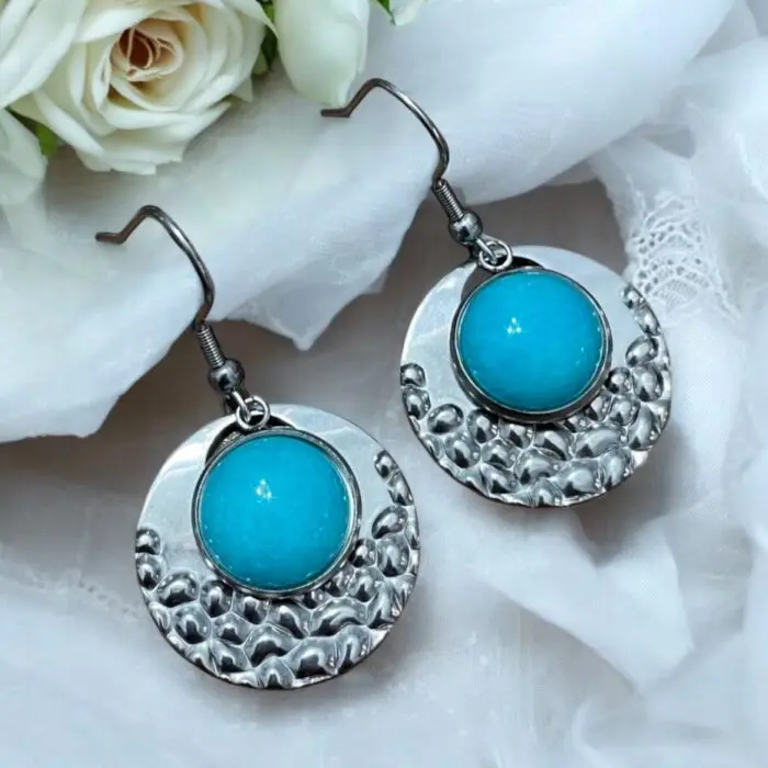 These stunning silver and turquoise earrings featuring a chic circular design with a popcorn pattern. Crafted from durable stainless steel and adorned with beautiful jade stones, they offer a perfect blend of elegance and modern flair