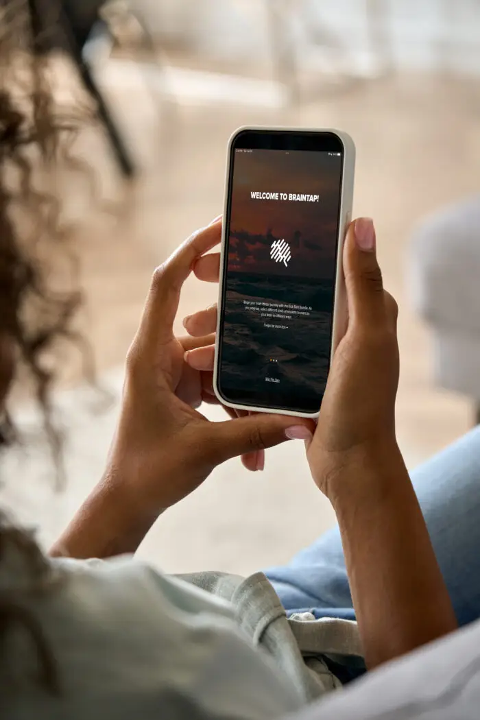 Woman holding a phone with the BrainTap App Screen